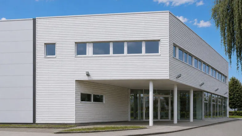 Modernes Geschäftsgebäude mit weißer Fassade, großen Fenstern und einem einladenden Eingangsbereich.