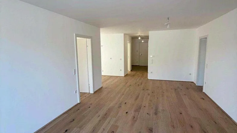 Geräumiger, heller Wohnbereich mit neuem Holzboden und weiß gestrichenen Wänden, bereit zum Einzug.