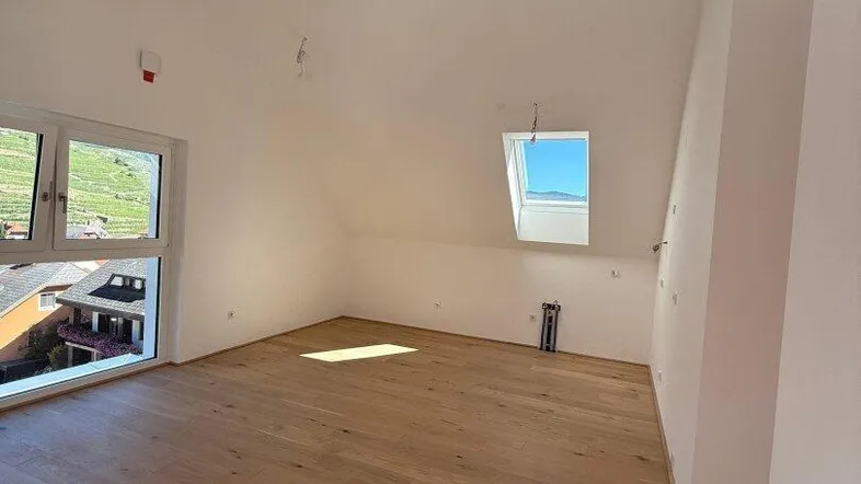 Heller, geräumiger Raum mit Holzboden, Dachschrägen, sichtbarem Holzbalken und weitem Blick.