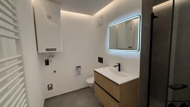 Modernes Badezimmer mit elegantem Waschtisch, begehbarer Dusche und indirekter Beleuchtung.
