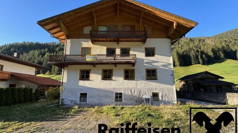 Traditionelles alpines Wohnhaus mit Holzbalkonen und Blick auf die umliegende Berglandschaft.