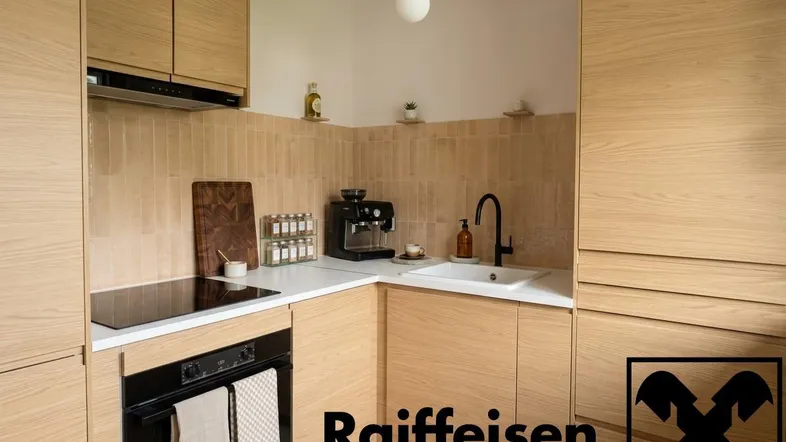 Moderne Küche mit hellen Holzfronten, weißer Arbeitsplatte und integrierten Geräten.