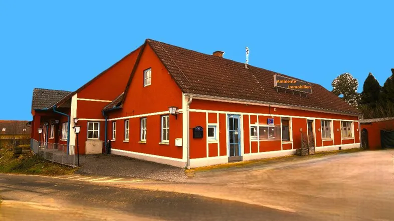 Rotes Gebäude mit weißer Fassadenverzierung und braunem Dach, das einen traditionellen Stil aufweist.