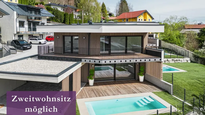 Moderne Villa mit Holzfassade, privatem Pool und gepflegtem Garten in sonniger Hanglage.
