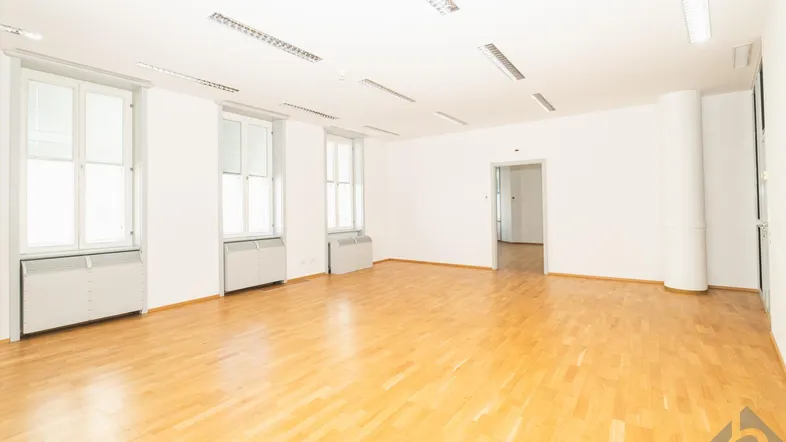 Geräumiger, leerer Büroraum mit hellem Parkettboden und großen Fenstern, bereit zur individuellen Gestaltung.