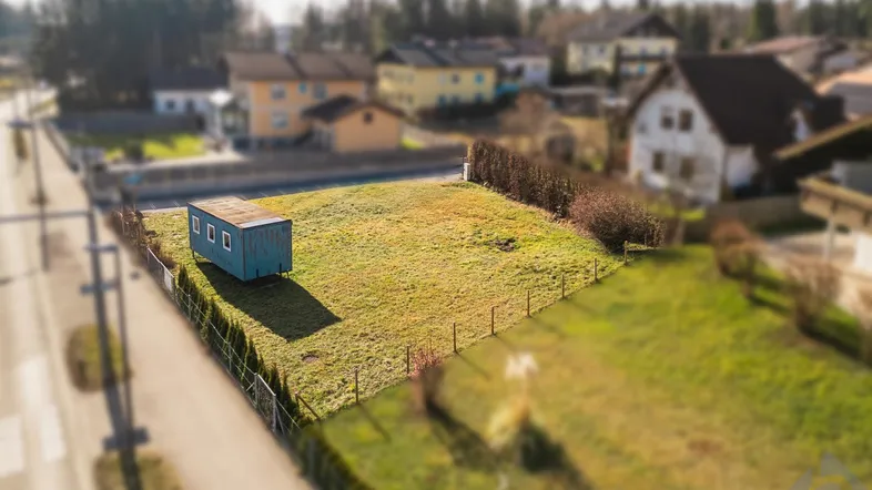 Luftaufnahme eines Baugrundstücks mit kleinem Container und umliegenden Häusern in ländlicher Umgebung.