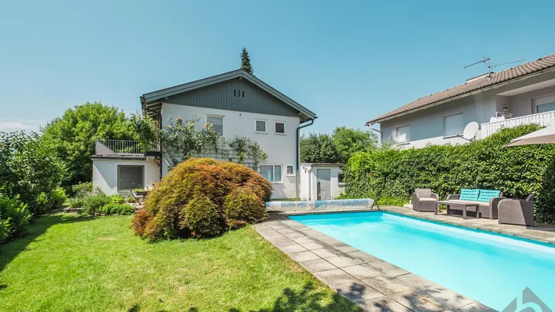 Gepflegter Gartenbereich mit großem Swimmingpool, Liegewiese und gemütlicher Sitzecke im Freien.