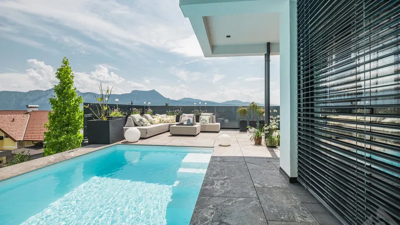 Große Dachterrasse mit Infinity-Pool, gemütlicher Lounge und atemberaubendem Bergblick.