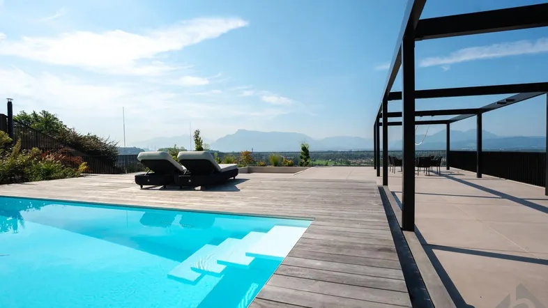 Großzügiger Außenbereich mit Pool, Holzdeck und Liegestühlen, umgeben von einer malerischen Berglandschaft.