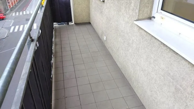 Balkon mit Fliesenboden und Blick auf die Straße, ideal für entspannte Stunden im Freien.