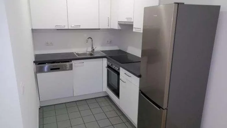 Moderne Einbauküche mit weißen Schränken, dunkler Arbeitsplatte und integrierten Geräten.