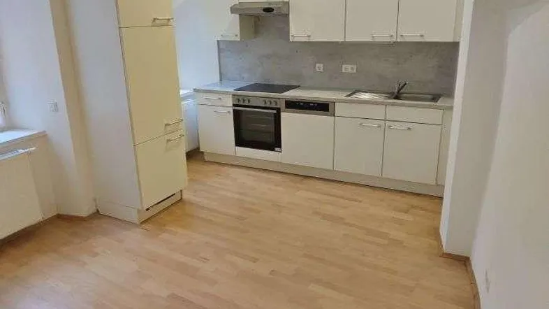 Helle Küche mit weißen Schränken, integrierten Geräten und hellem Holzfußboden.