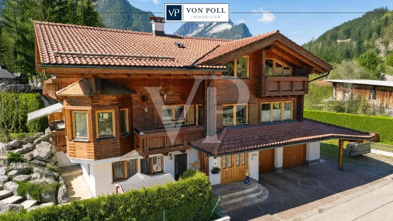 Traditionelles Holzchalet mit mehreren Balkonen, Ziegeldach und Bergblick in alpiner Umgebung.