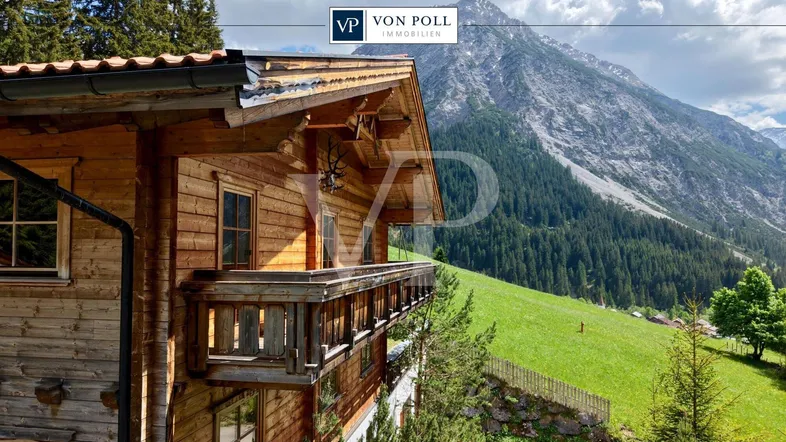 Traditionelles Holzchalet mit Balkon und atemberaubendem Blick auf die umliegende Berglandschaft.