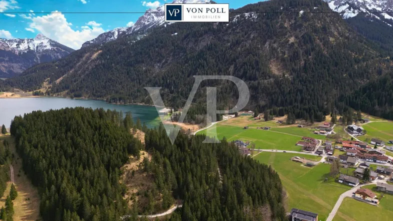 Atemberaubende Luftaufnahme einer malerischen Berglandschaft mit See, Wäldern und einem charmanten Dorf.