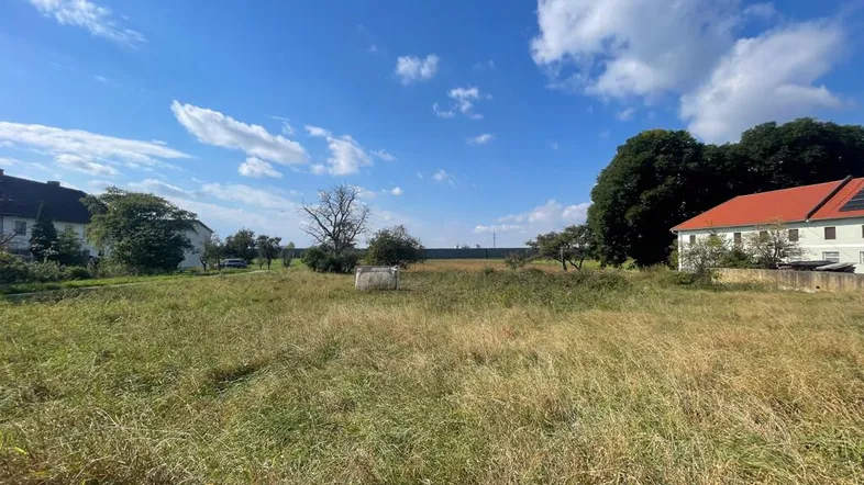 Weitläufiges Wiesengrundstück mit Blick auf umliegende Gebäude und weiten Himmel.