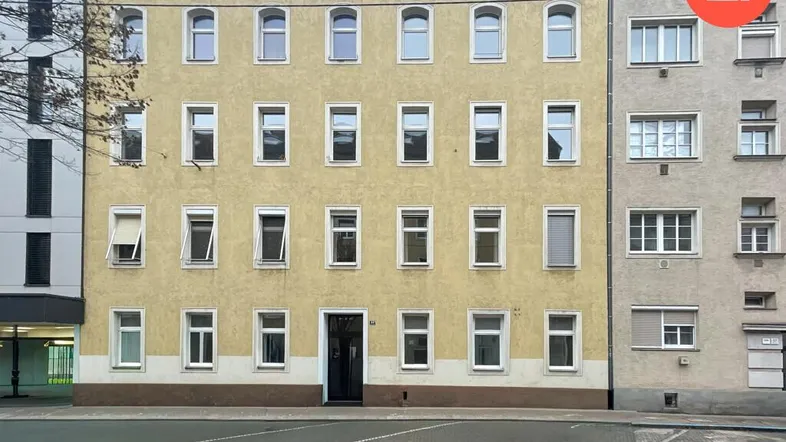 Die Fassade des Mehrfamilienhauses mit vielen Fenstern und klassischer Architektur.