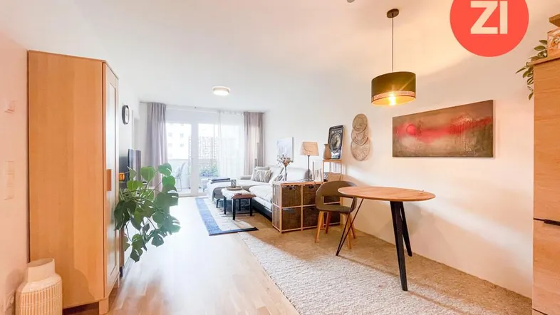 Geräumiger Wohn- und Essbereich mit Holzboden, Teppich und Zugang zum Balkon.