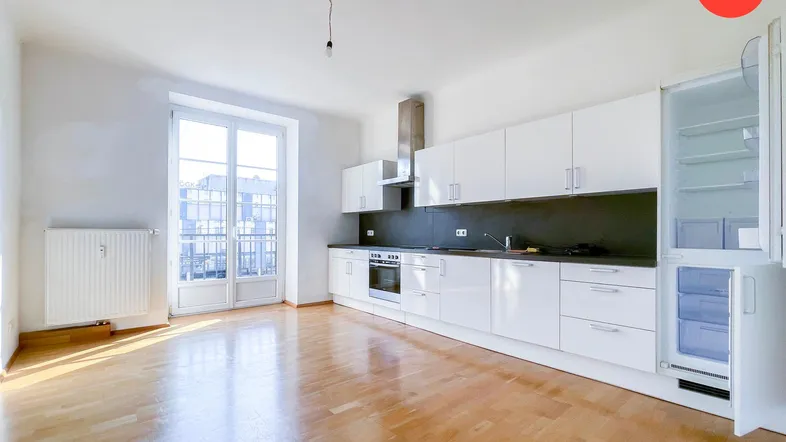 Helle Wohnküche mit modernen weißen Hochglanzschränken, Holzboden und Zugang zu einem französischen Balkon.