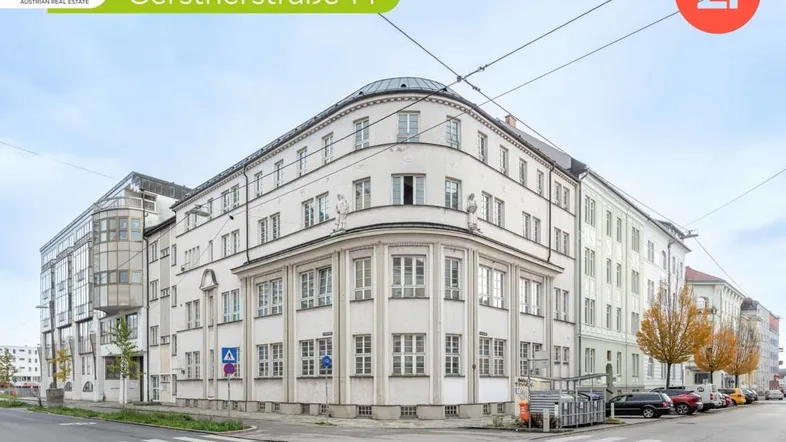 Eckgebäude mit klassischer Architektur und modernen Anbauten an einer städtischen Kreuzung.
