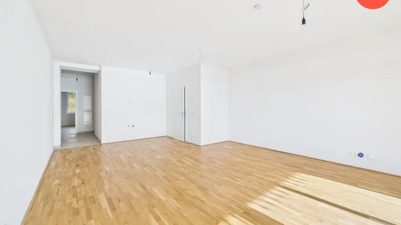 Helles, leeres Zimmer mit neuem Parkettboden und weißen Wänden, bereit zum Einzug.