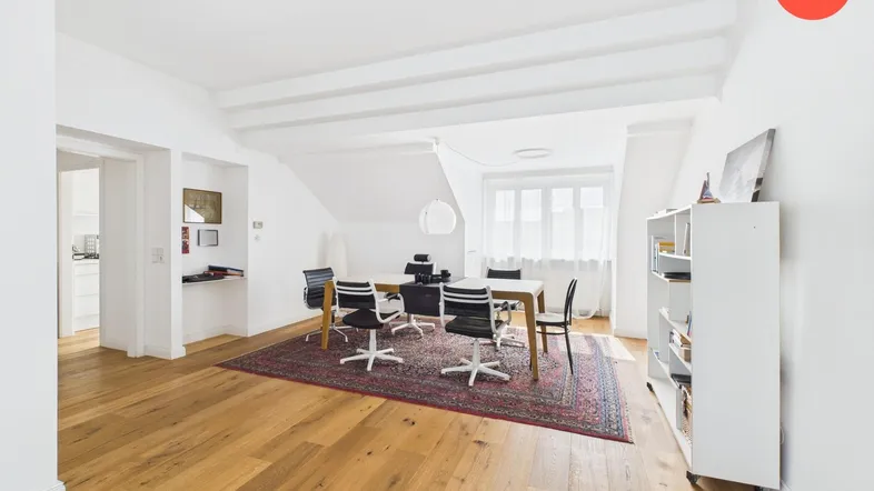 Heller Wohn- und Essbereich mit Holzboden, sichtbaren Deckenbalken und viel Tageslicht.