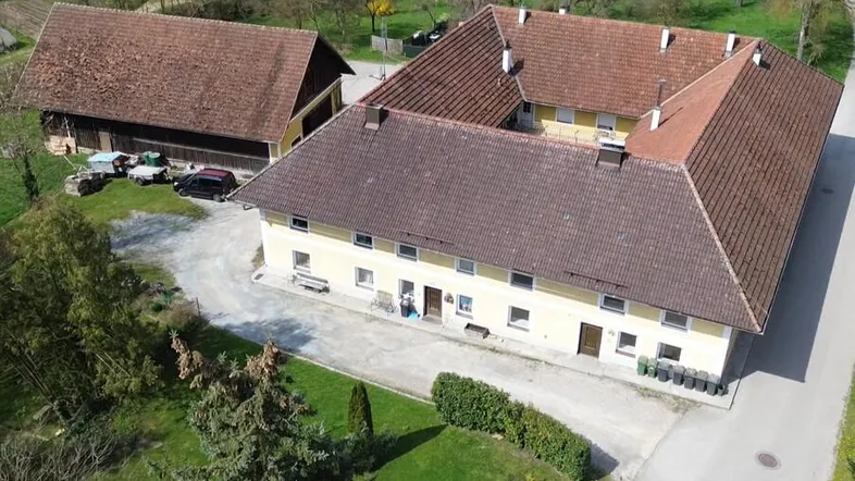 Luftaufnahme eines großen, U-förmigen Gebäudekomplexes mit Innenhof und angrenzender Scheune.