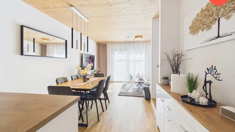 Heller offener Wohn-Essbereich mit Holzboden, Holzdecke und modernem Esstisch.