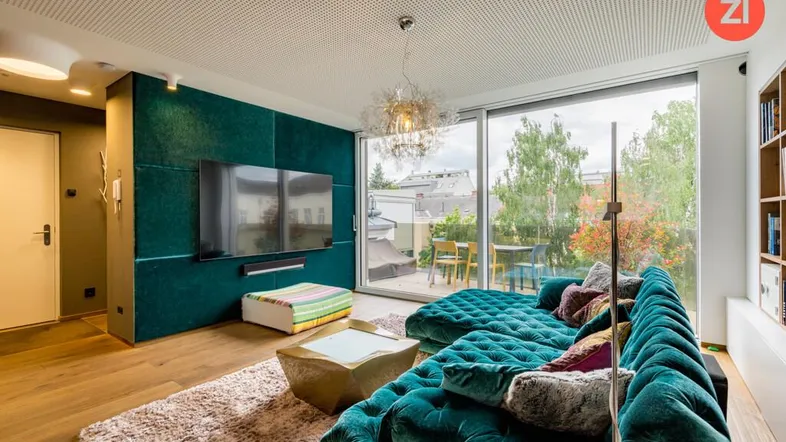 Modernes Wohnzimmer mit großer türkiser Samtcouch, Holzboden und Zugang zur Terrasse.