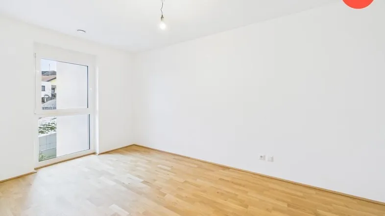 Helles Zimmer mit Holzboden und großem Fenster, bereit für die individuelle Gestaltung.
