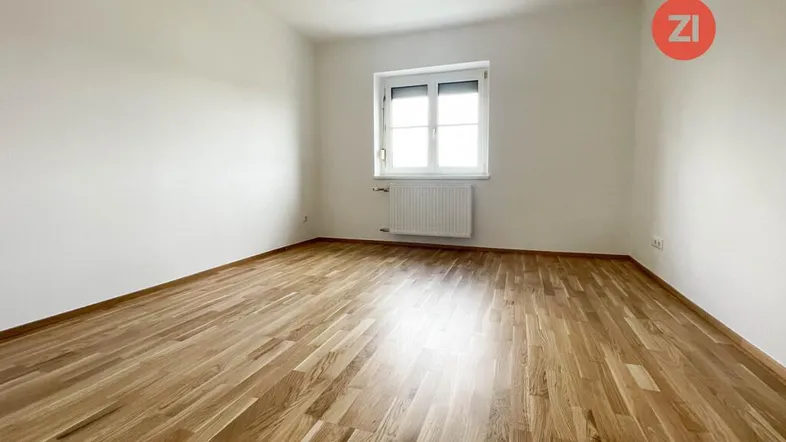 Helles, leeres Zimmer mit Parkettboden und einem Fenster, bereit zur individuellen Gestaltung.