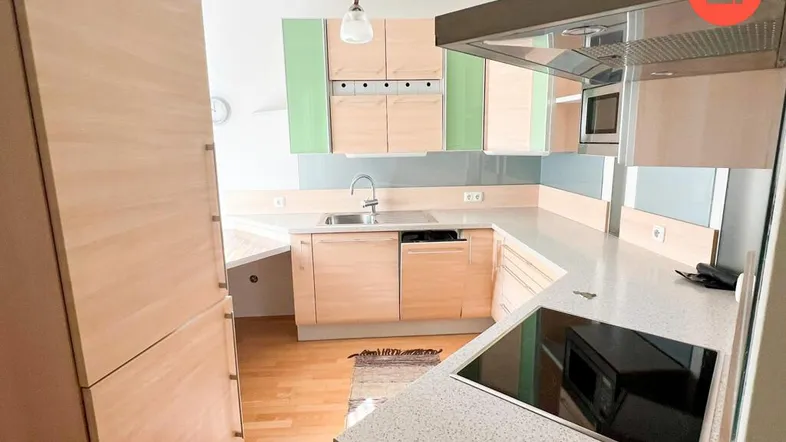 Moderne Küche mit hellen Holzfronten, grünen Akzenten und integrierten Geräten.
