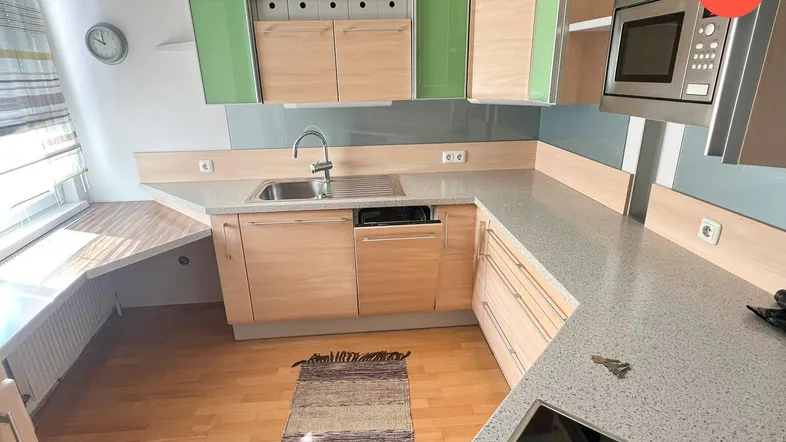 Moderne Küche mit hellen Holzschränken, grünen Akzenten, Induktionskochfeld und Fenster.