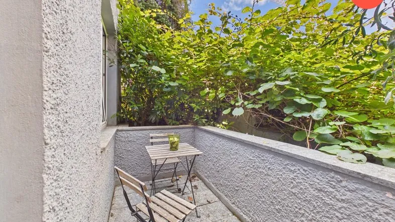 Kleiner, gemütlicher Balkon mit Sitzgelegenheiten und üppiger grüner Bepflanzung für entspannte Stunden im Freien.