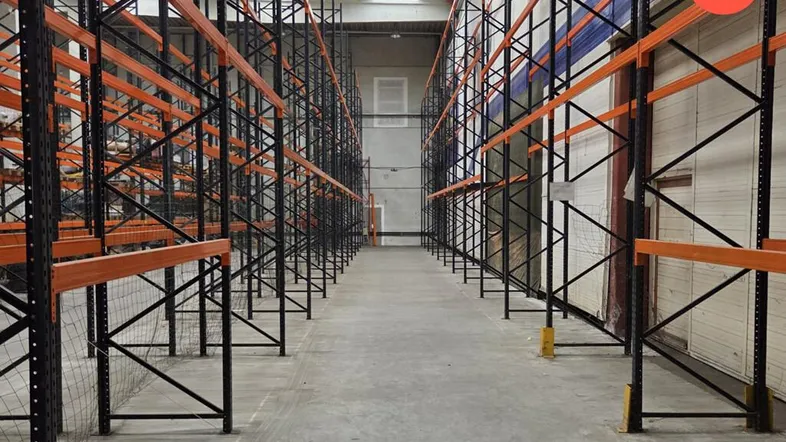 Geräumige Lagerhalle mit hohen Decken, Betonboden und industriellen Regalsystemen für effiziente Lagerung.
