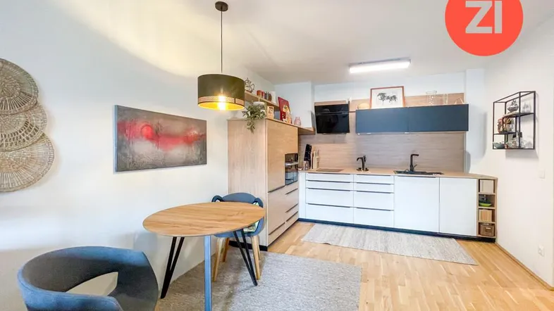 Moderne Küche mit hellen Holzfronten, integrierten Geräten und kleinem Essbereich.