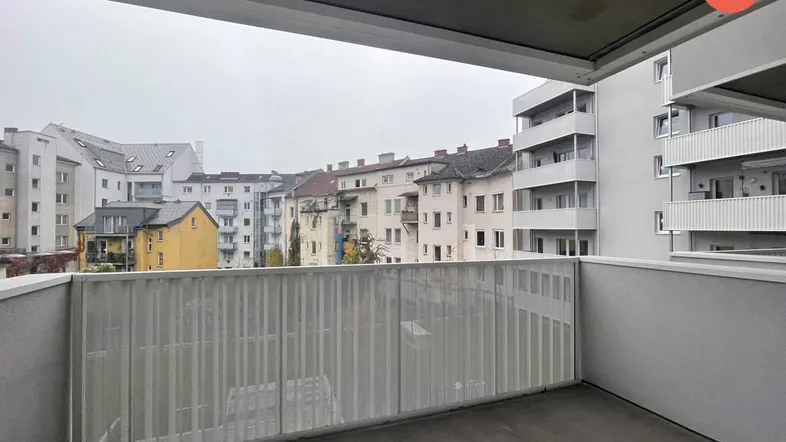Balkon mit Blick auf umliegende Wohngebäude und grauen Himmel in städtischer Umgebung.