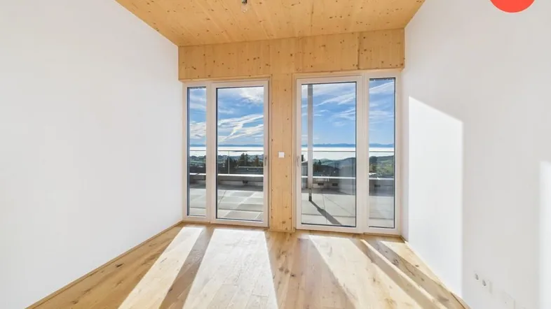 Helles Zimmer mit Holzboden und Holzdecke, großen Fenstern und weitem Ausblick.