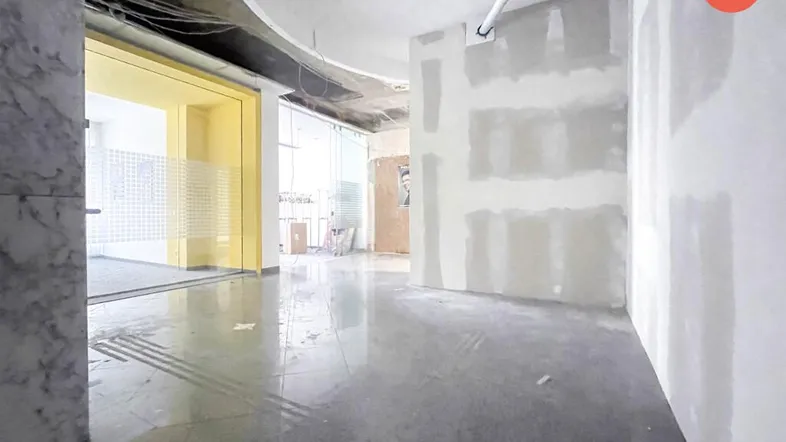 Unfertiger Gewerberaum mit großen Glasfronten und sichtbaren Trockenbauwänden, bereit für den Ausbau.