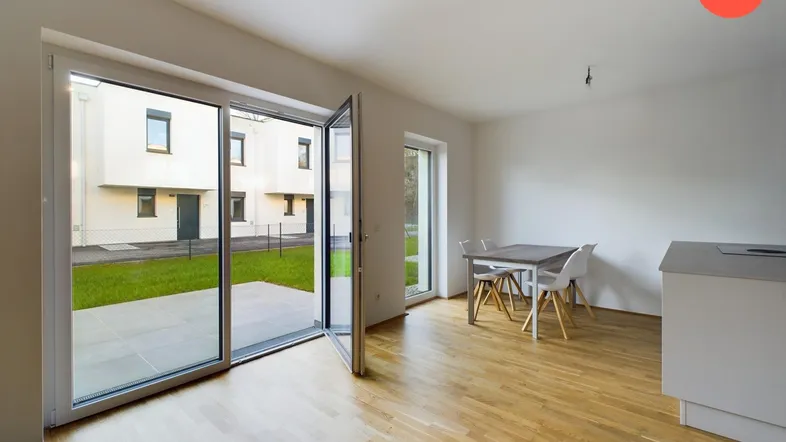Heller offener Wohnbereich mit Holzboden, Zugang zur Terrasse und Blick auf den Garten.
