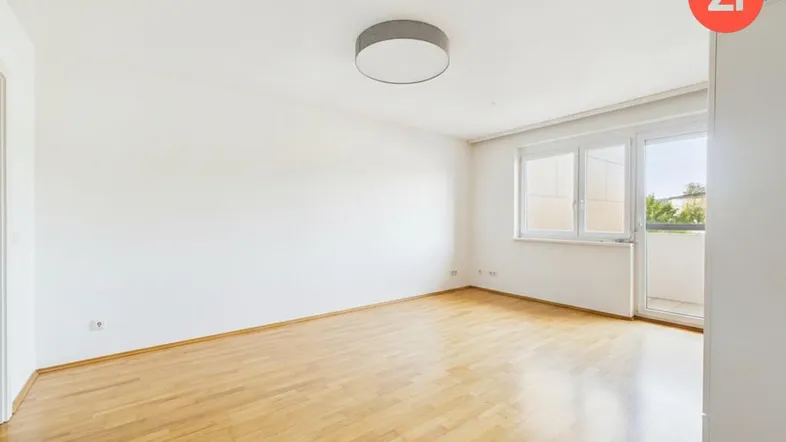 Heller Wohnraum mit Parkettboden, großen Fenstern und direktem Balkonzugang.