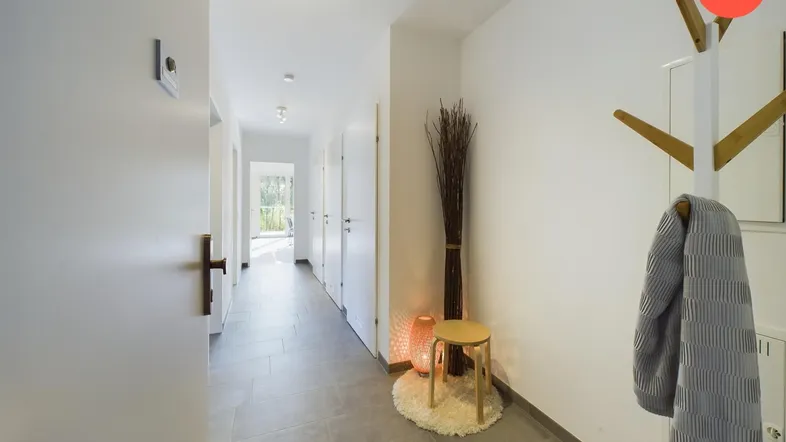 Heller Flur mit modernen Fliesenboden, Garderobe und indirekter Deckenbeleuchtung.