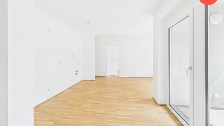 Geräumiger, heller Wohnbereich mit Holzboden und großen Fenstern, bereit für individuelle Gestaltung.