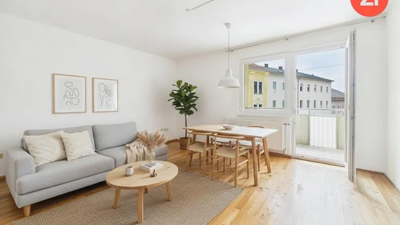 Helles Wohn- und Esszimmer mit Holzboden, moderner Einrichtung und Zugang zu einem Balkon.