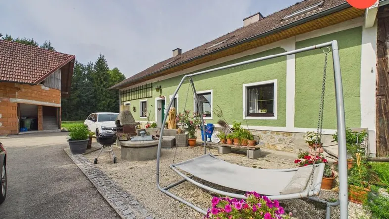 Ländliches Anwesen mit grün gestrichenem Haus, Gartenbereich und Grillplatz im Freien.
