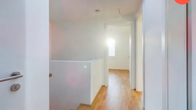 Heller Flur mit Holzparkettboden, Oberlicht und Treppenaufgang, der viel Tageslicht hereinlässt.