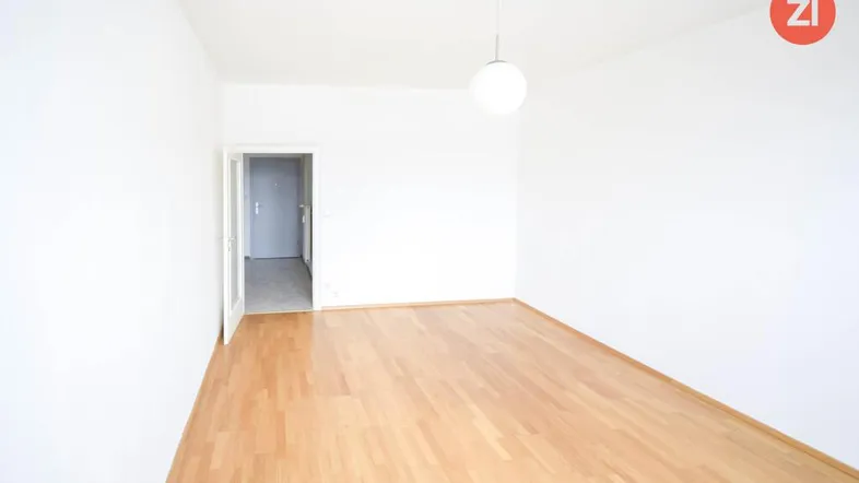 Helles, leeres Zimmer mit Parkettboden und Zugang zu einem Flur, in gutem Zustand.