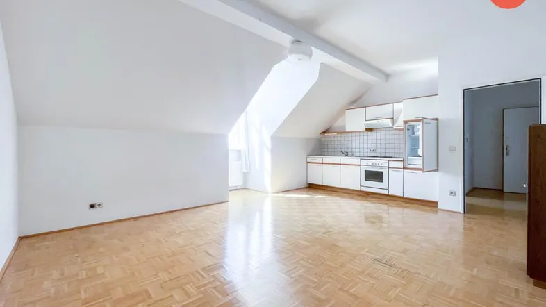 Helles Wohnzimmer mit Parkettboden, Dachschrägen und integrierter Küchenzeile in einem Dachgeschoss.