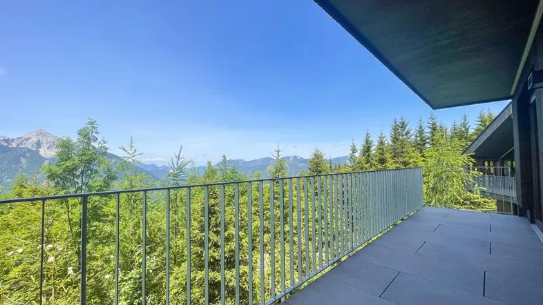 Großer Balkon mit Fliesenboden und Metallgeländer bietet einen atemberaubenden Blick auf die Berge und Wälder.