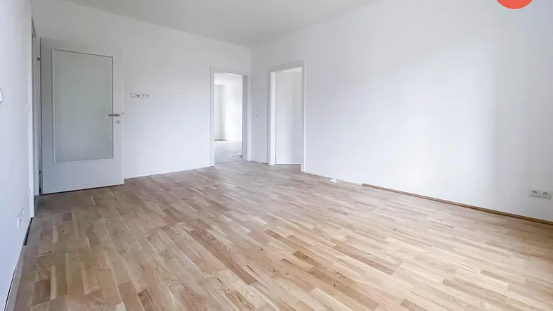 Helles, leeres Wohnzimmer mit hellem Parkettboden und weißen Wänden, bereit zur Einrichtung.